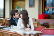 Dating couple kissing in a Parisian cafe