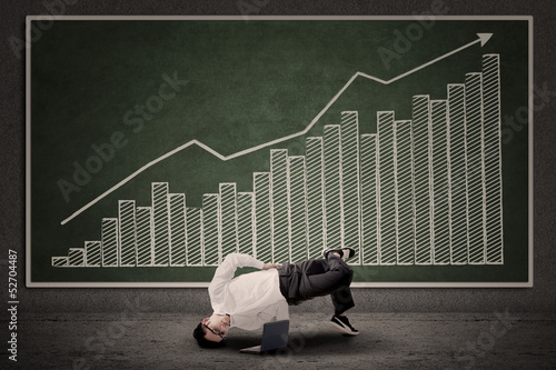 Photo: Businessman dancing in front of profit bar chart Businessman dancing in front of profit bar chart