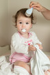 Mother combing her baby girl's hair with hairbrush after shower