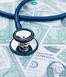 Medical stethoscope on dollar bills.