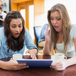 Women looking shocked at tablet pc in canteen