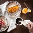 Hand pouring milk on coffee on a romantic breakfast table