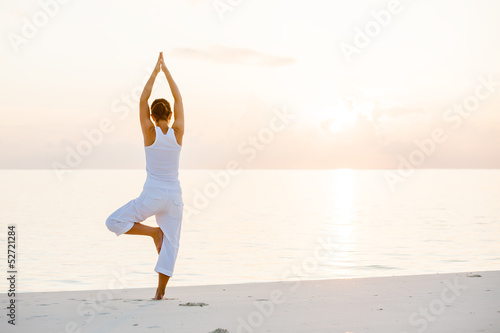 Photo: Caucasian woman practicing yoga at seashore Caucasian woman practicing yoga at seashore
