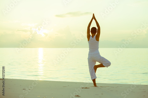 Photo: Caucasian woman practicing yoga at seashore Caucasian woman practicing yoga at seashore