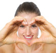 Photo: Smiling young woman looking through heart shaped hands Smiling young woman looking through heart shaped hands