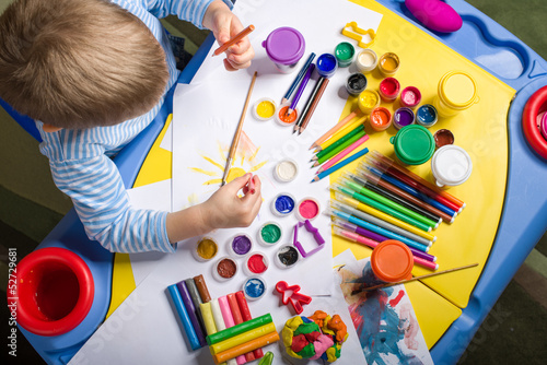 Photo: little boy painting at the table, top view little boy painting at the table, top view