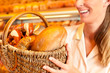 Photo: Female baker selling bread by basket in bakery Female baker selling bread by basket in bakery
