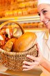 Female baker selling bread by basket in bakery