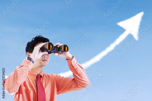 Photo: Businessman see success arrow sign using binocular Businessman see success arrow sign using binocular
