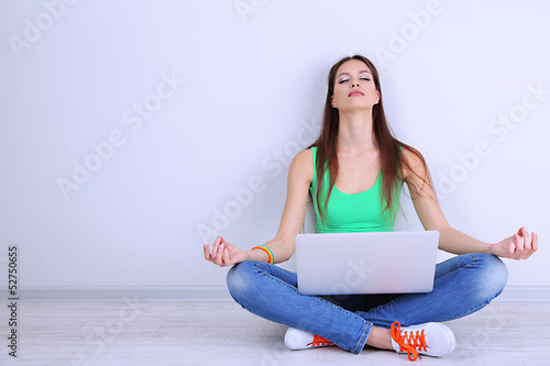 Photo: Beautiful young woman sitting with laptop in room Beautiful young woman sitting with laptop in room