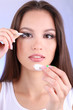 Young woman putting contact lens in her eye close up
