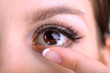 Young woman putting contact lens in her eye close up