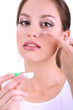 Young woman putting contact lens in her eye close up