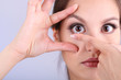 Young woman putting contact lens in her eye close up