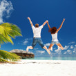 Happy couple jumping in the tropical beach