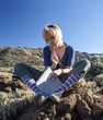 Girl is sitting on the rock and thinking with notebook