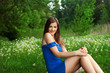Beautiful girl sitting at the field of withered dandelions