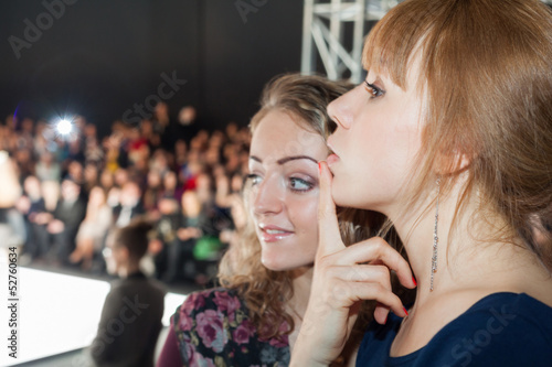 Photo: Two beautiful girls watching a fashion show. Two beautiful girls watching a fashion show.