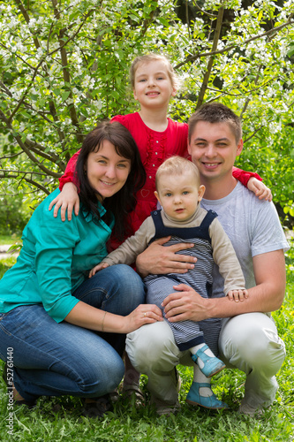 Photo: Happy family of four walking in the park. Happy family of four walking in the park.