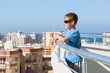A boy stands on balcony of hotel and looks into distance