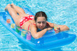 Woman swimming in pool on inflatable mattress with drink