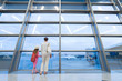 Mother and daughter looking out window at airport terminal