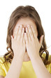 Young teen woman covering her face with hands
