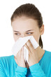 Young woman with tissue - sneezing. Allergy or cold.