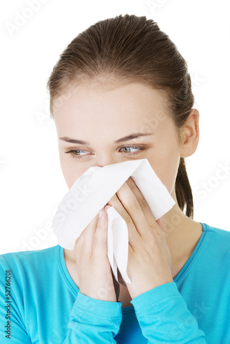 Photo: Young woman with tissue - sneezing. Allergy or cold. Young woman with tissue - sneezing. Allergy or cold.