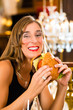 Photo: Young woman in fine restaurant, she eats a burger Young woman in fine restaurant, she eats a burger