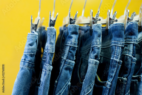 Photo: Row of hanged blue jeans in a shop Row of hanged blue jeans in a shop