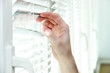Someone looking out of window opening blinds