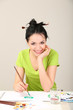 Beautiful young woman painter at work, on color background