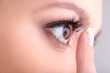 Photo: Young woman putting contact lens in her eye close up Young woman putting contact lens in her eye close up