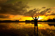 Silhouette of Man with his hands up watching the sun set