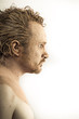 man covered in mud, naked, in profile, dirty skin