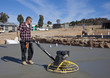Workman smoothing newly poured concrete for housing estate