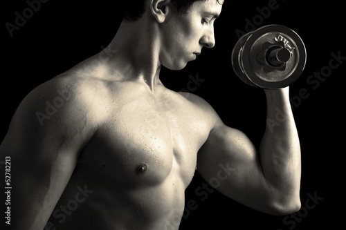 Photo: Closeup of a muscular young man lifting weights Closeup of a muscular young man lifting weights