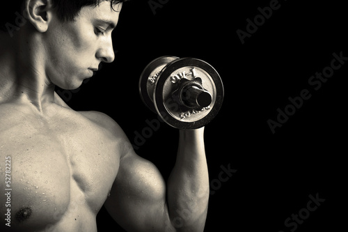 Photo: Closeup of a muscular young man lifting weights Closeup of a muscular young man lifting weights
