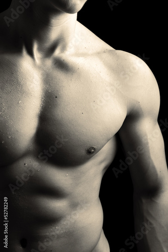 Photo: Man with naked muscled torso against black background Man with naked muscled torso against black background