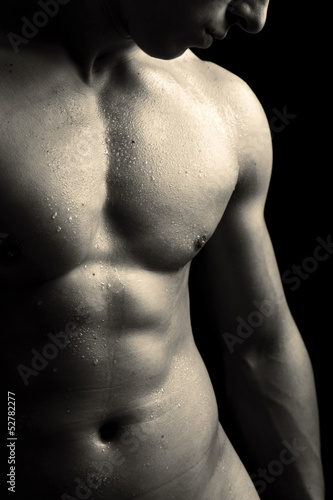 Photo: Man with naked muscled torso against black background Man with naked muscled torso against black background