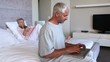 Couple relaxing in bed and man doing his own thing