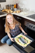 Happy woman cooking raw fish in oven