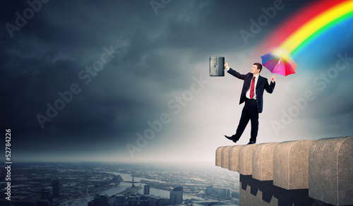 Photo: Businessman with umbrella atop of building Businessman with umbrella atop of building