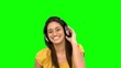 Woman smiling and listening to music on green screen