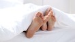 Pair of feet playing footsie under the covers