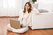 Young woman sitting on floor with a laptop