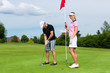 Photo: Young sportive couple playing golf on a course Young sportive couple playing golf on a course
