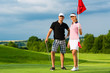 Photo: Young sportive couple playing golf on a course Young sportive couple playing golf on a course