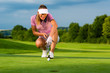 Photo: Young female golf player on course aiming for her put Young female golf player on course aiming for her put
